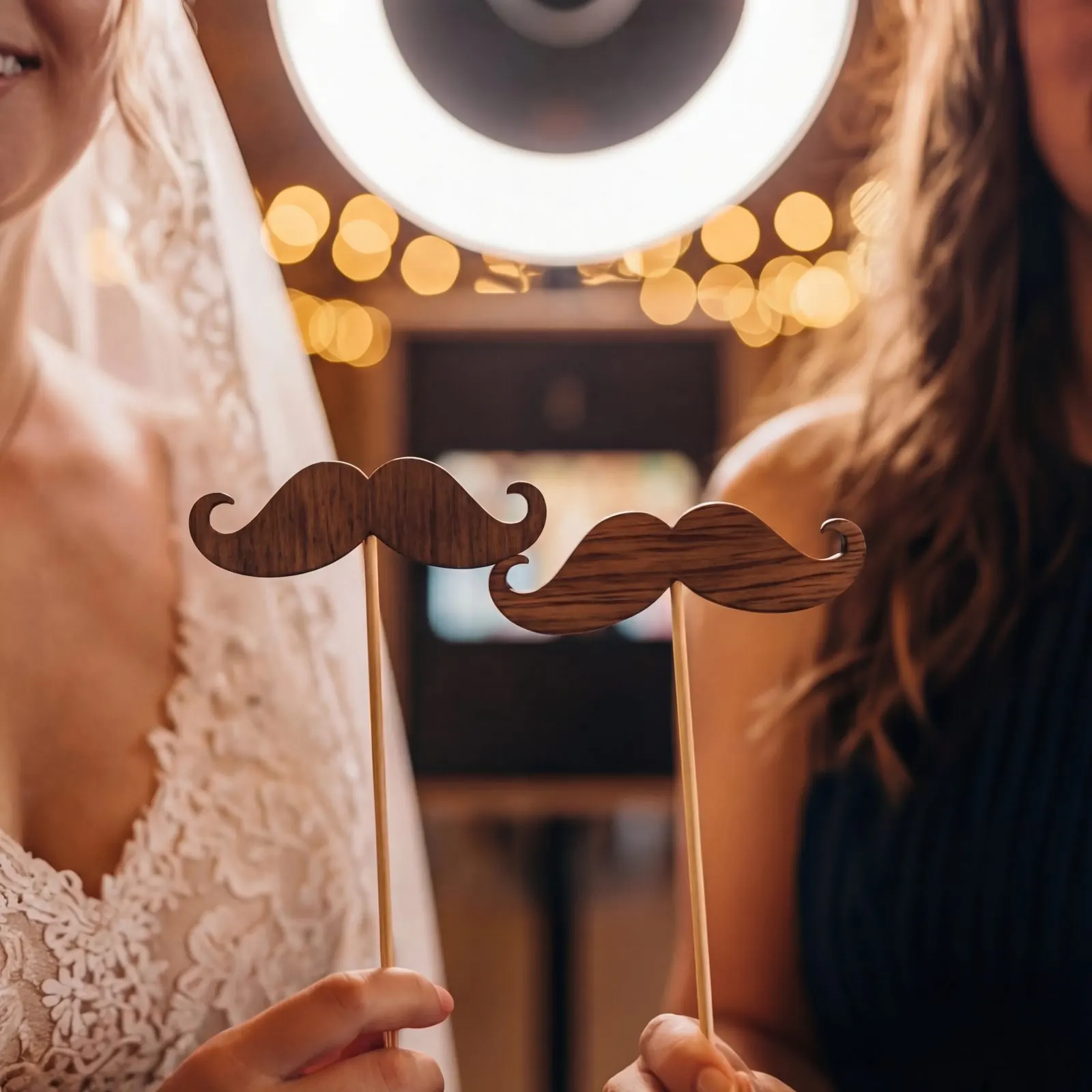 Brautpaar mit Schnurrbart-Requisiten an der Fotobox mit Ringlicht